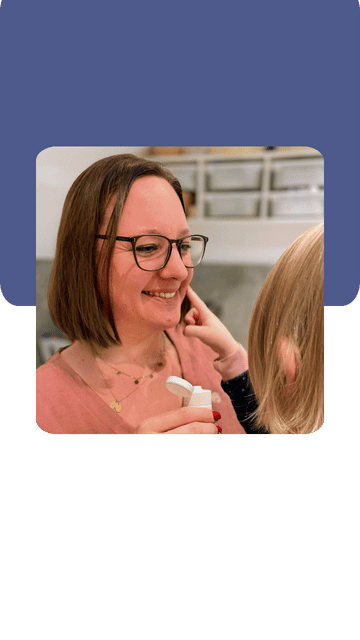 liebevoll aufwachsen – Caroline Bechmann lächelt beim Eincremen mit einem Kind in einem familiären Alltagsmoment